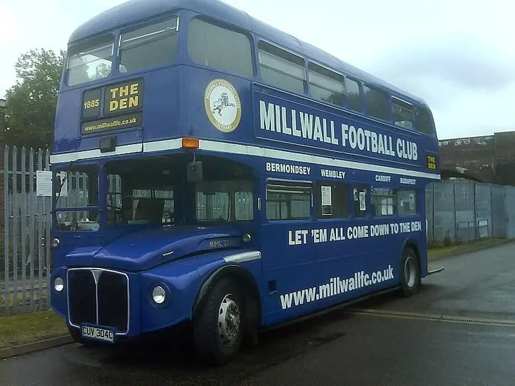 Chiếc xe buýt Routemaster mang logo Millwall FC, biểu tượng di chuyển của đội bóng và người hâm mộ.