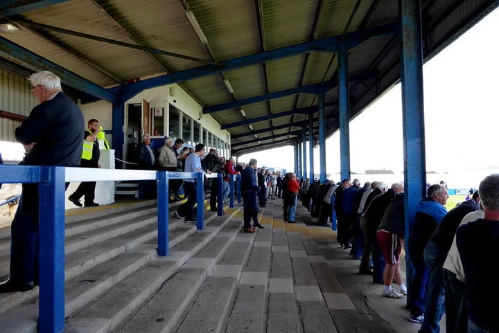 Cổ động viên Barrow AFC đứng trên khán đài, hòa mình vào không khí trận đấu tại Holker Street