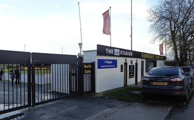 Cổng vào sân Wetherby Road, lối vào quen thuộc dẫn đến EnviroVent Stadium, nơi đón chào những người hâm mộ Harrogate Town trong mỗi trận đấu tại League Two, mang đậm dấu ấn thời gian.