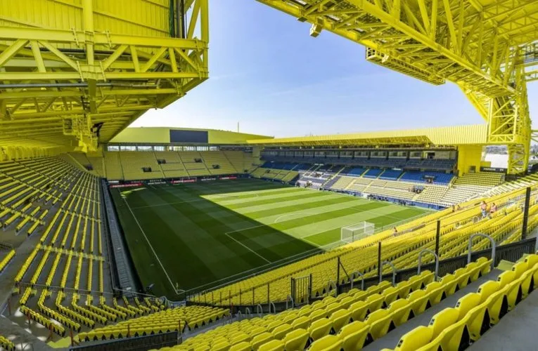 Góc nhìn từ khán đài bên trong sân vận động Estadio de la Ceramica, cận cảnh sân cỏ và các hàng ghế.