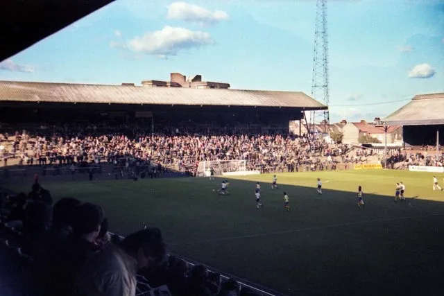 Khán đài Hammersmith End của Craven Cottage vào thập niên 1980, tái hiện không khí sân cỏ cổ điển.