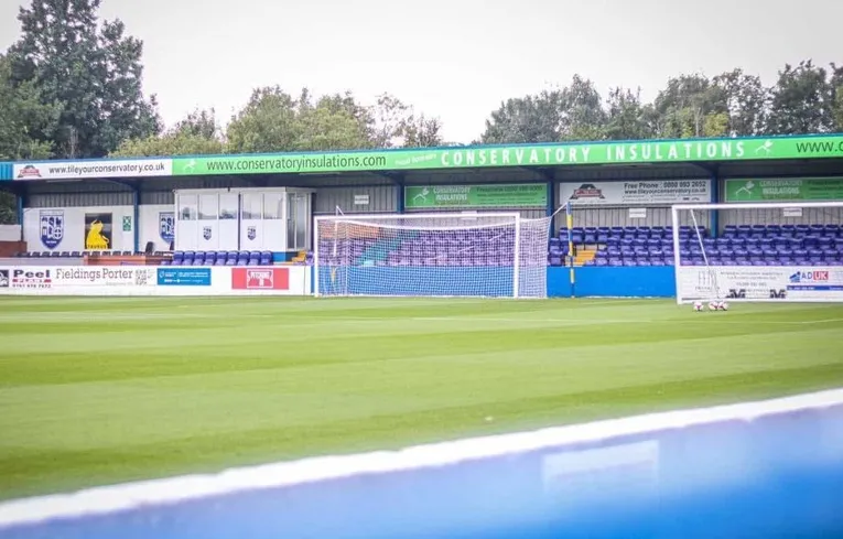 Khán đài Lodge End Stand ở phía sau khung thành sân Stainton Park, với hàng ghế xanh đơn giản và không khí vắng lặng