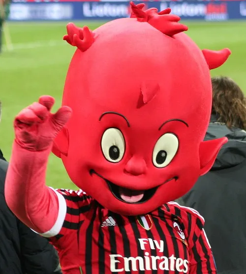 Linh vật của AC Milan, Il Diavolo, đang vẫy chào người hâm mộ, một biểu tượng của tinh thần Rossoneri trên sân nhà San Siro.