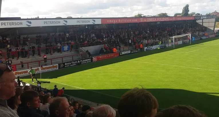 Sân Mazuma Mobile trong ngày thi đấu, khán giả lấp đầy một góc khán đài, tạo nên không khí bóng đá đặc trưng