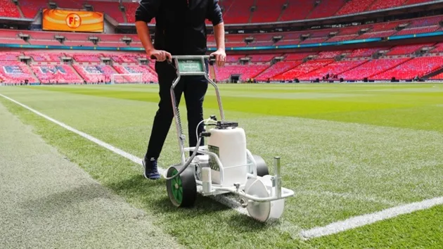 Công nhân chăm sóc mặt cỏ và hệ thống đèn trên sân vận động