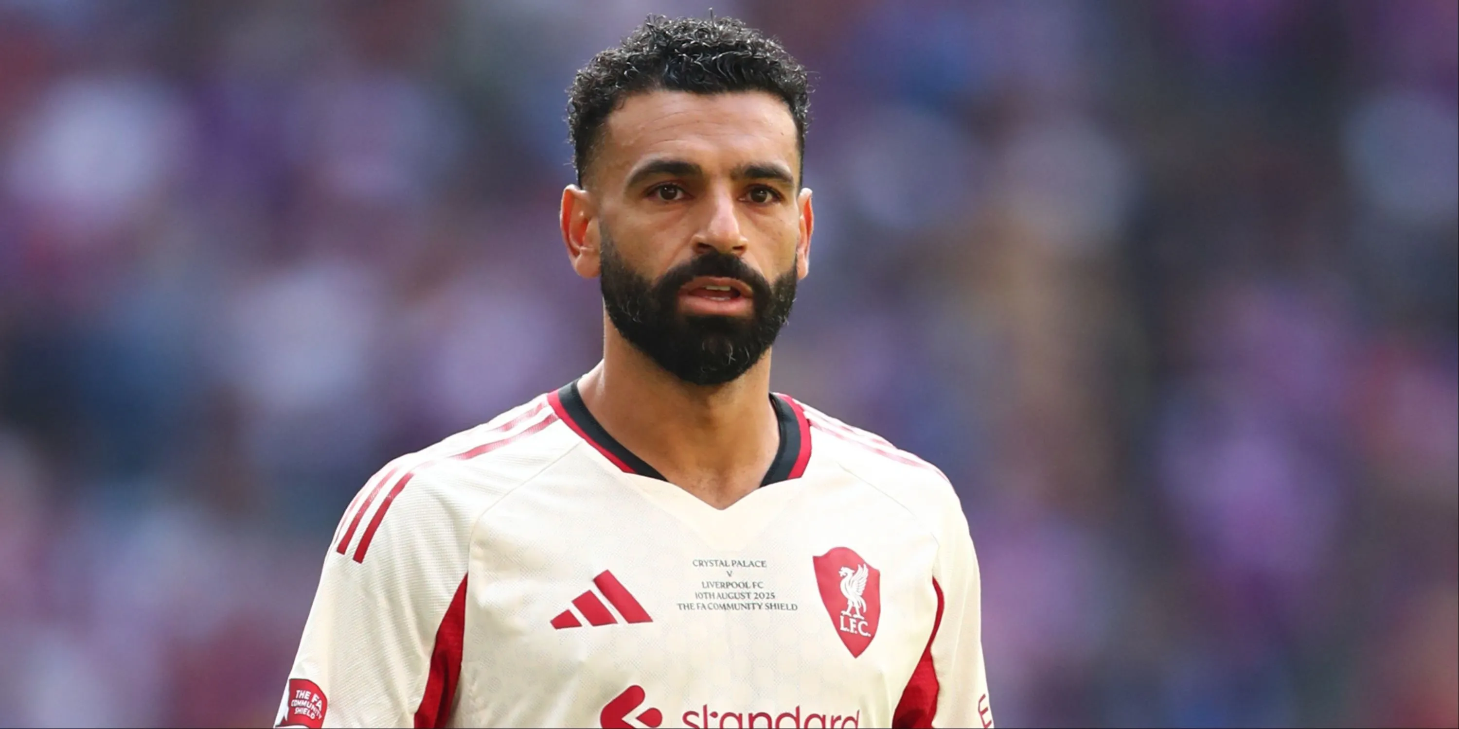 Mohamed Salah đứng giữa sân với vẻ mặt trầm tư trong một trận đấu